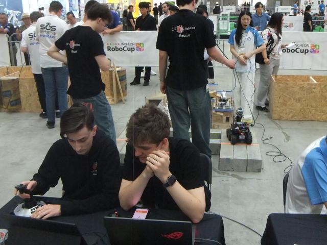 Die beiden Operateure sitzen mit dem Rücken zum Parcours, auf dem der CJT-Roboter seine Aufgaben erledigt.